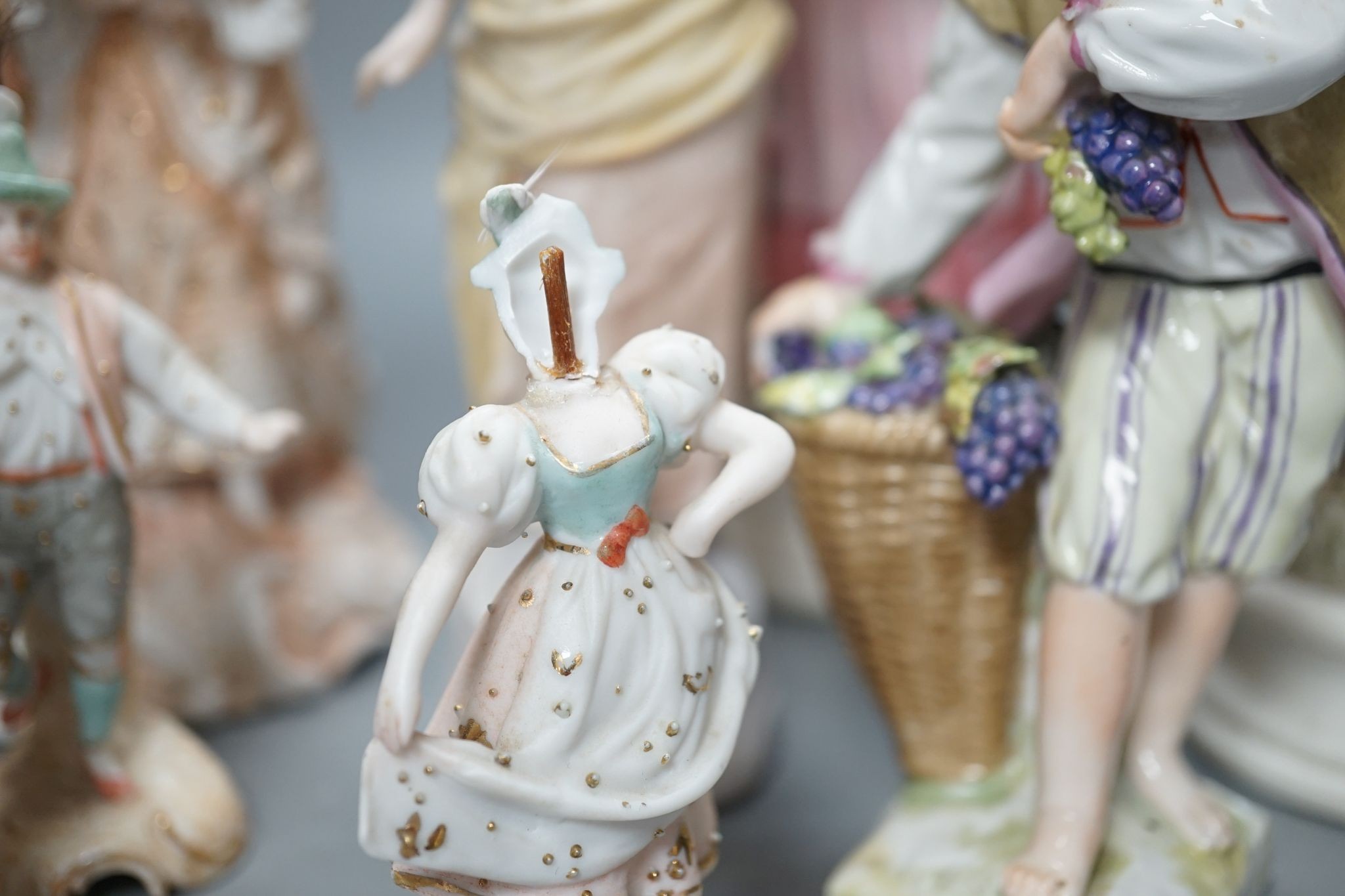 Ten French bisque figures and a Berlin figure of a grape picker, tallest 19cms high.